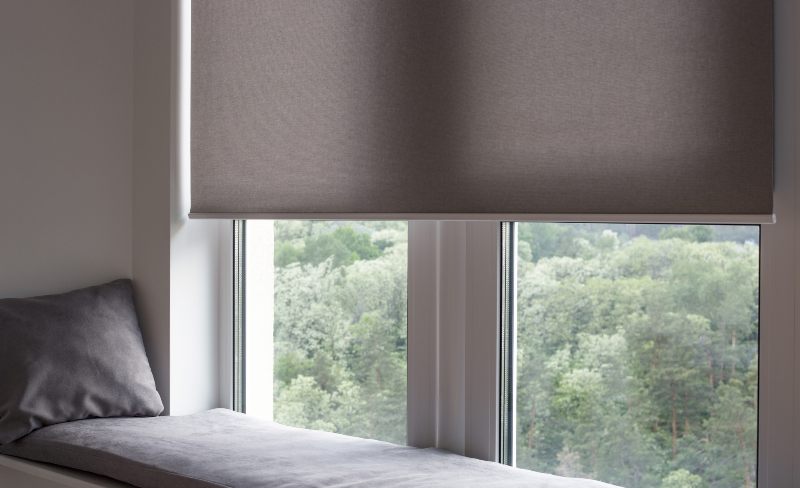 Motorized shades half-drawn beside sofa overlooking Scottsdale AZ and Boerne TX forested lawn.